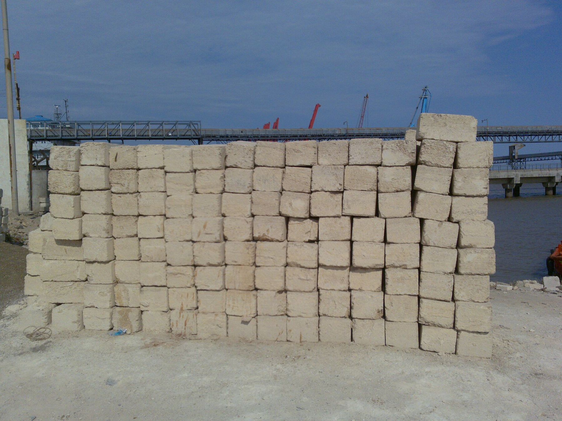 Cut limestone blocks stacked near the port, a jetty behind